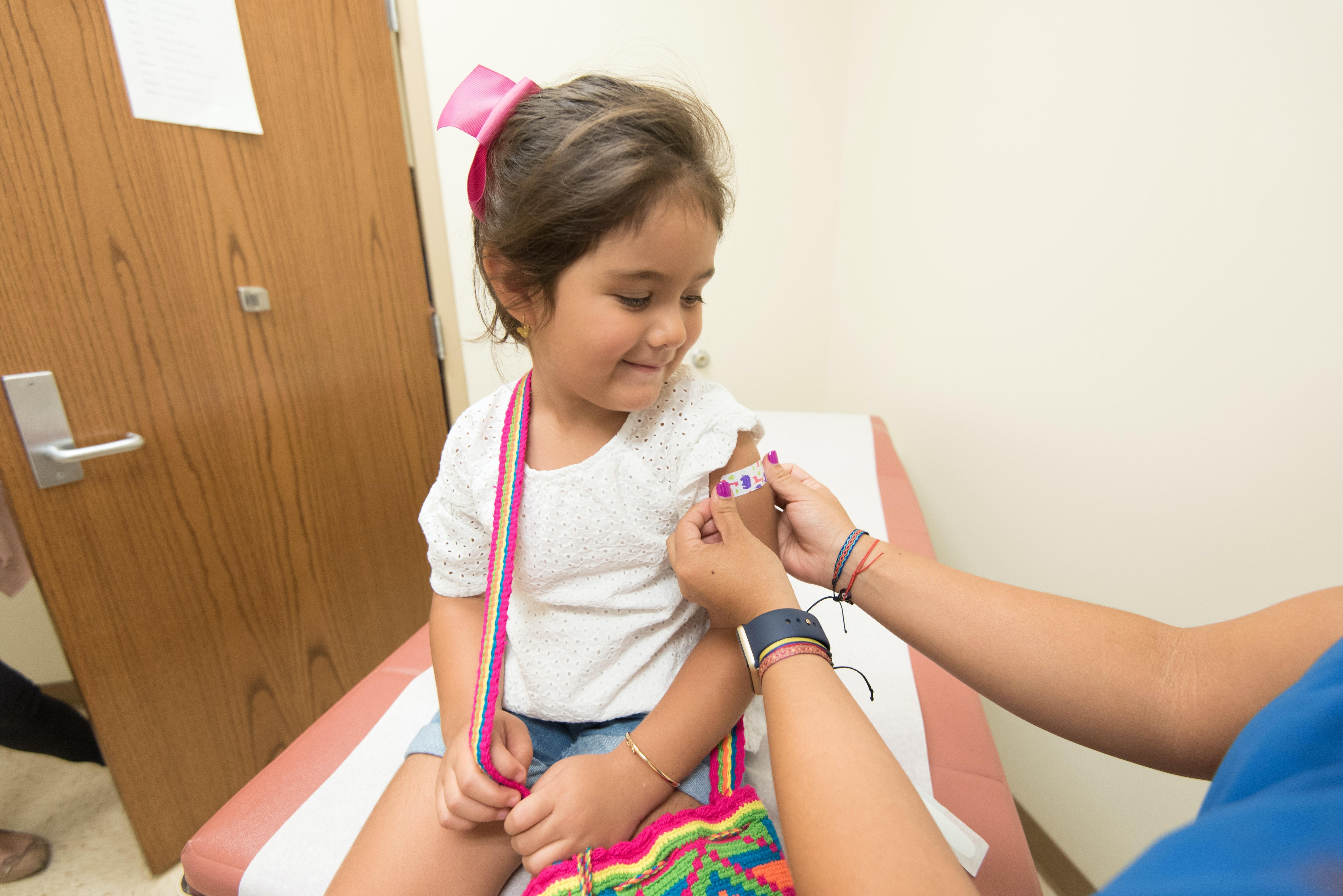 child getting a shot from a nurse